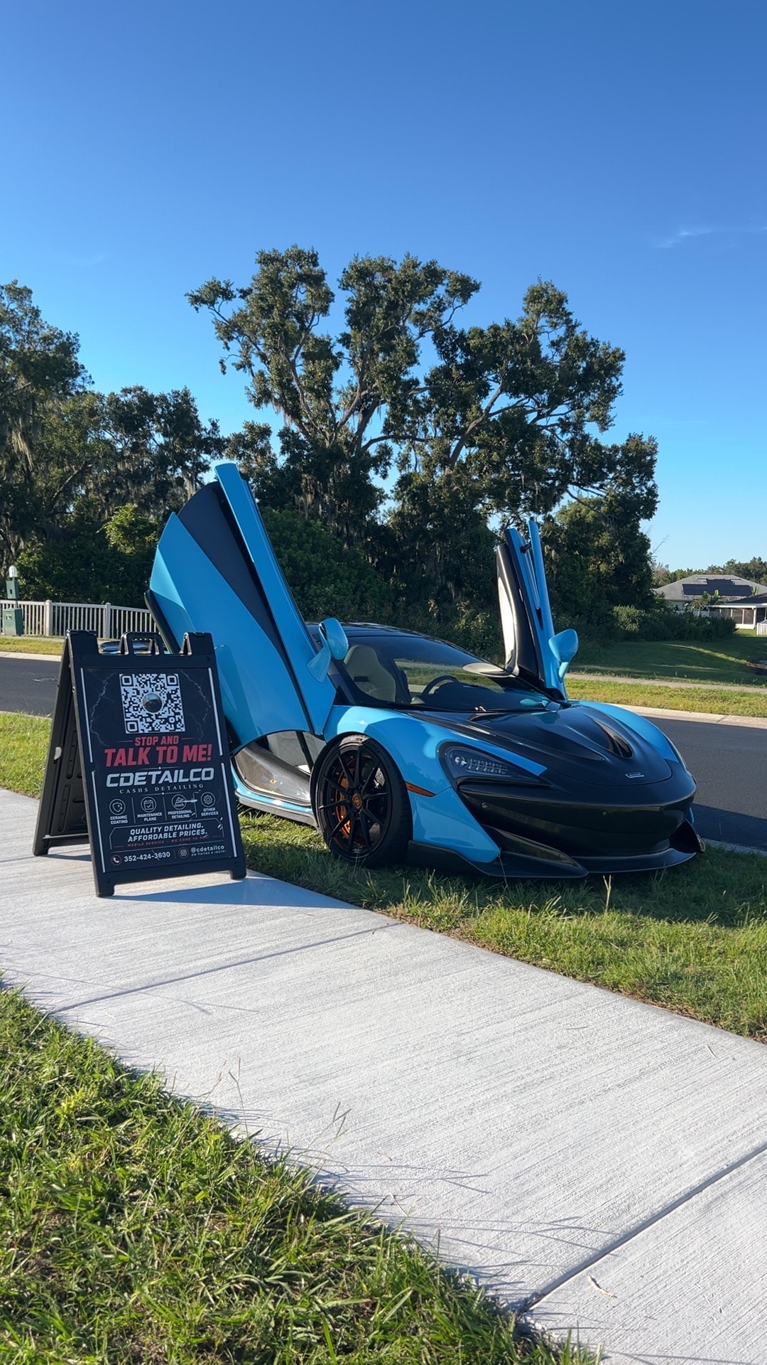 Cyan and black McLaren with doors open after a glossy exterior detail